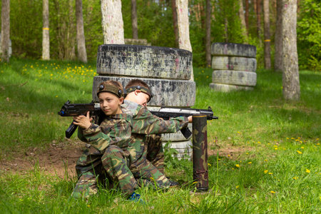 Two boys weared in camouflage playing laser tag in special forest playground. Laser Tag is a command military tactical game using safe laser weapons and sensors that record hits.の写真素材