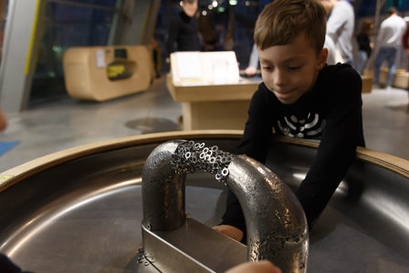 A boy plays with metal objects on a stand with a large magnet demonstrating the structure of the magnetic field at a scientific and educational exhibition.の写真素材