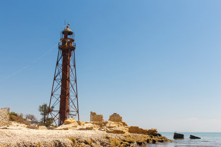 An old eifell lighthouse with a red roof on the seashore Jarylgach island, Ukraine. Seascape with copy space. Postcard from travel.の写真素材