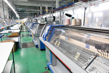 A row of industrial textil flat knitting machines in a knitwear factory. An industrial line of...