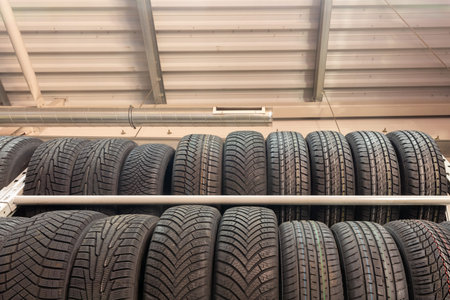 Car tires on rack in auto store. Two rows of tires on the shelves in the store against the...