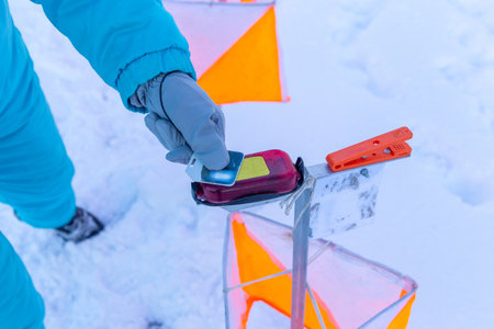 A competitor in an orienteering competition applies a wireless chip to the starting mark to start the countdown. Winter orienteering.の写真素材
