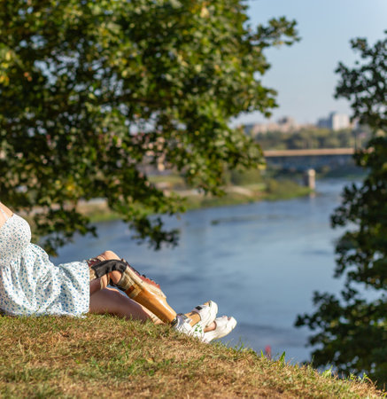 Beautiful young woman leg amputee in a dress walking in park near by river at sunny day. Life goes on no matter what.の写真素材