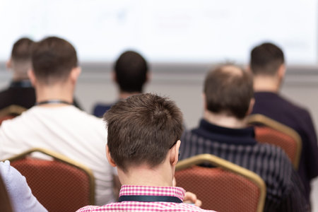 Back view of audience in a business conference or seminar. Audience listens to the lecturer at the...