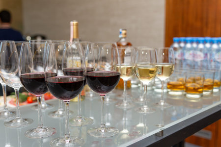 A lot of glasses with various alcoholic beverages stand on the bar. Various alcoholic beverages in glasses at buffet on party.の写真素材