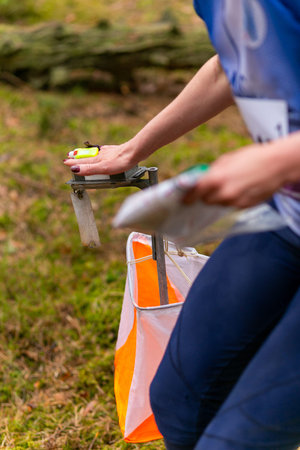 A woman punching at the orienteering control point close up. Female in forest checking to a control point. Selective focusの写真素材