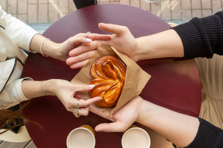 A guy with a girl on a date in a cafe. The guy hands the girl a heart-shaped bun.の写真素材