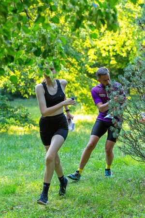 Grodno, Belarus - 26 June, 2024: Strong caucasian teenage girl wearing sportswear running through a park during exercise in outdoor orienteering Street-O. Hobby sport.のeditorial素材
