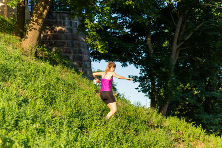 Grodno, Belarus - 26 June, 2024: Cute young caucasian women wearing sportswear running through a forest during exercise in outdoor orienteering Street-O. The map in her hands. Hobby sport.のeditorial素材