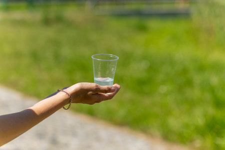 A volunteer hand holds a plastic cup of water for runners at triathlon competitions.の写真素材