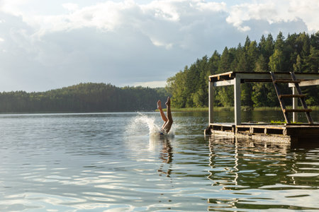 Kids jumping in lake water at summer holiday. The concept of a happy carefree childhood.の写真素材