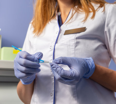 Doctor in gloves holds brush for smears and glass in laboratory. Doctor gynecologist holding cytobrush over slide glass in clinic closeupの写真素材