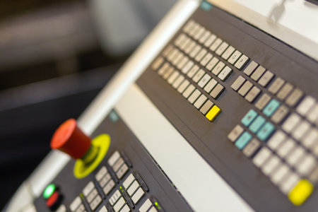 Control panel of cnc turning milling lathe machine at factory, plant, red emergency switch button on foreground - close up side view. Panel with button for controlling production machines.の写真素材