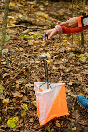 A woman punching at the orienteering control point close up. Female in forest checking to a control point. Selective focusの写真素材