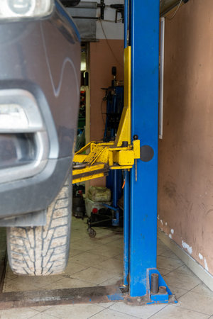 Gray car on auto lift in garage for repair and maintenance service. Car raised on a lift in an auto repair shop, ready for inspection and maintenance.の写真素材