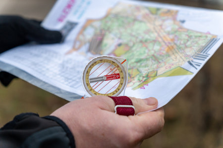 Athlet holding a map and the compass during orienteering competitions. Athlete uses navigation equipment for orienteering,compass and topographic map.の写真素材
