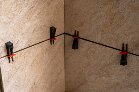 Tile leveling system with plastic clips and wedges, shot while the tile mortar sets. Wall tiling.