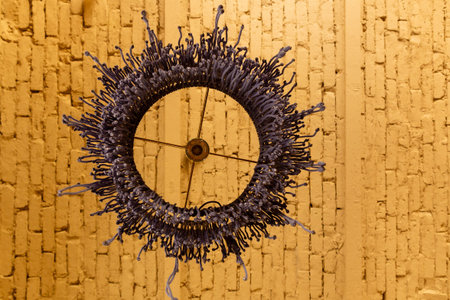 Macrame lampshade with fringes, suspended in front of a warm, background. Hand crafted blue macrame...