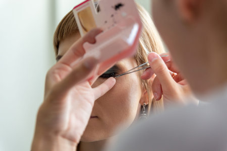 Makeup artist applying false eyelash. Professional visagiste working making extension lashes....