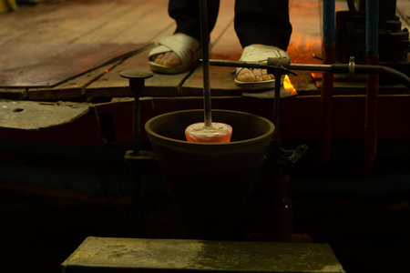 A mesmerizing close-up of a skilled artisan blowing molten glass into shape, capturing the artistry and precision of the glass manufacturing process.の写真素材