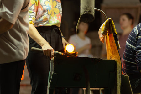 A glass blower is working on the manufacture of glass vases and glasses.Cooling of an incandescent product with water. Up to 20 workers can be involved simultaneously in the production of particularly complex products.の写真素材