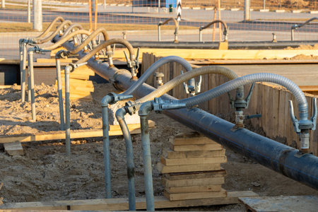 A close-up view of a series of flexible hoses connected to a pipe at a construction site,...