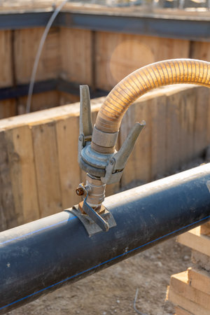 A close-up view of flexible hose connected to a pipe at a construction site, illustrating the setup...