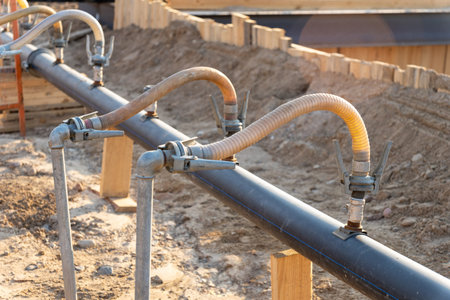 A close-up view of a series of flexible hoses connected to a pipe at a construction site,...
