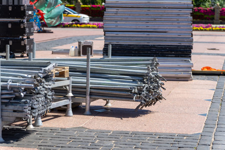 Stacked metal structures for assembling an open-air concert stage, ready for construction. Industrial event setup with beams, frames, and staging materials.の写真素材