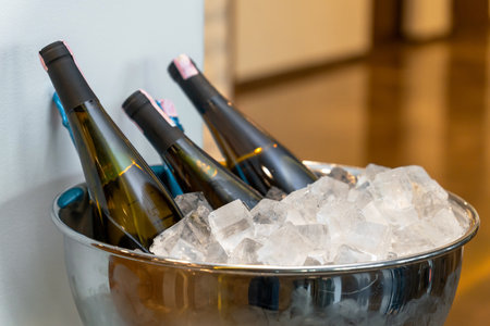 Elegant banquet setup with wine and champagne bottles chilling in a large ice bowl, displayed in a luxurious hotel lobby for guestsの写真素材
