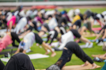 A blurred, indistinct crowd of people participating in a large group activity or exercise class at a stadium on a sunny summer day.の写真素材