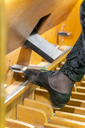 A close-up shot of a musician's foot pressing the pedals of a majestic, antique pipe organ during a performance in a historic Lutheran church.の写真素材