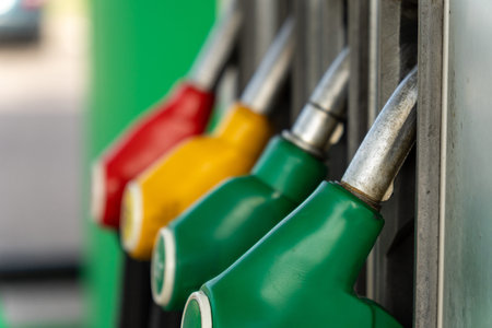 Close-up of four fuel dispensing nozzles on a gas pump, ready for refueling. A detailed view of...