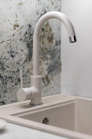 Modern kitchen faucet on a sleek artificial stone sink. Clean design, bright countertop with a functional water tap.の写真素材