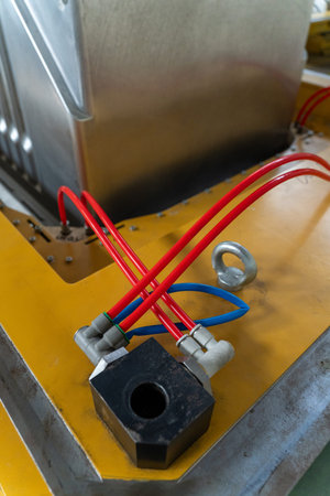 A close-up of a pneumatic system on an industrial machine used in a refrigerator factory. Red and blue air hoses connect to a metal block on a yellow base, highlighting precision and technology on the assembly line.の写真素材