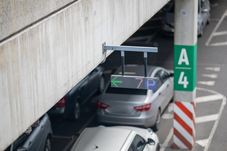 A modern car park with a digital LED sign, highlighting urban infrastructure and parking guidance technology. The multi-story concrete structure and clear signage create a graphic, functional aesthetic.の写真素材