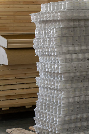 Furniture manufacturing factory interior with a stack of wooden frame, board, and white pocket...