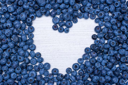 Heart shape with blueberries on wooden background top view. Concept for healthy.の写真素材