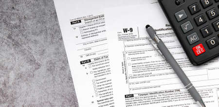 Tax relief and tax forms with a pen and a calculator to calculate taxes on a gray backgroundの写真素材