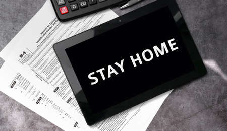 Stay home on a black tablet and with tax forms and calculatorの写真素材