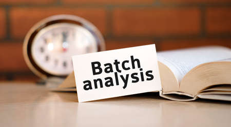 Batch analysis concept text on a white background with a clock and an open bookの写真素材