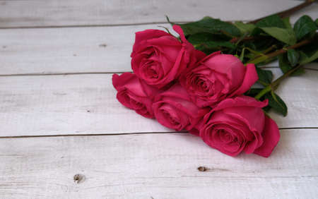 Red pink bouquet of roses on a wooden background with a place for textの写真素材