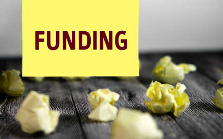 Funding - text on yellow note sheets on a dark wooden background with crumpled sheetsの写真素材