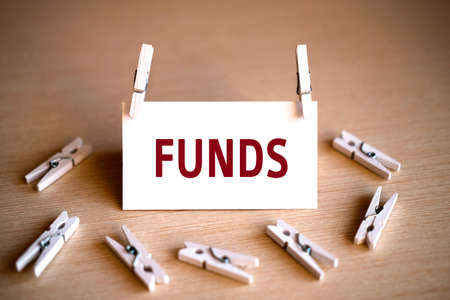Funds - text on a white background on a wooden table with lying clothespinの写真素材