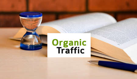 Organic seo traffic - business concept text on a white background with a hourglass and an open bookの写真素材