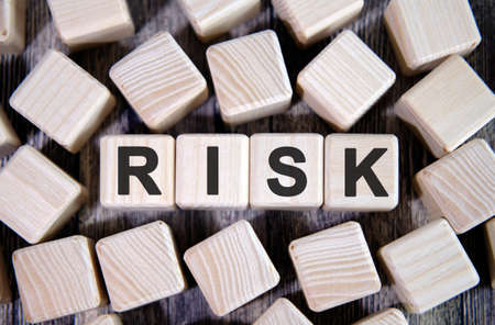 RISK - financial business concept, text on wooden cubes and many cubes around on a dark backgroundの写真素材