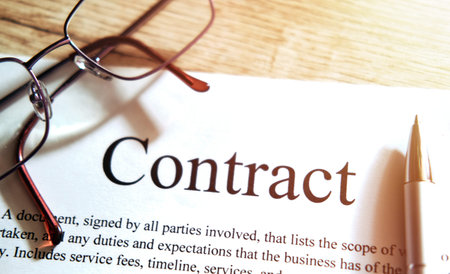 Contract sheet with glasses and a pen on a wooden background