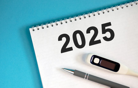 New year 2025 concept. Text on a notebook with a pen and a thermometerの写真素材