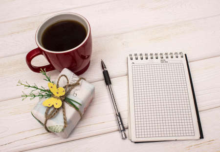 Notebook with coffee and gift box on a wooden table. Mock up photo on timbered background.の写真素材