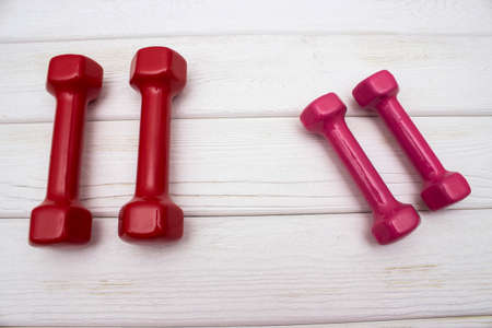 Red and pink dumbbells on a white wooden floorの写真素材